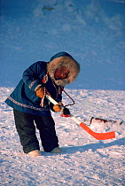 Inuit child playing with an ice hockey stick in Igloolik. Nunavut, Canada, 1987. Editorial use only.