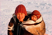 Inuit woman carrying her baby in an Amaut (hooded parka) on her back. Igloolik, Nunavut, Canada, 1987. Editorial use only.