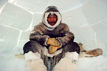 Inuk man from Igloolik sitting inside an Igloo. Nunavut, Canada, 1990. Editorial use only.