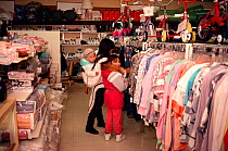 Inuit mother and girls shopping for clothes in a shop at Igloolik, Nunavut, Canada, 1990.