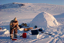 Inuit hunter refuelling a Coleman stove at his camp. Igloolik, Nunavut, Canada, 1990.
