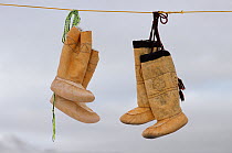 Sealskin Kamik (Inuit boots) hanging on a washing line to dry. Qikiqtarjuaq (Broughton Island), Nunavut, Canada, 2002.