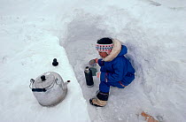 Inuit girl collecting water through hole in lake ice. Baffin Island, Nunavut, Canada, 1992.