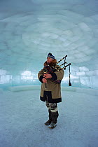 John MacDonald, a Scot who lives in Canada's arctic, playing the bagpipes in a large igloo. Nunavut, Canada, 1999.