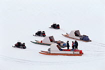 Snow-mobiles pulling sleds with family boxes on the sea ice. Bylot Island, Nunavut, Canada, 1999.