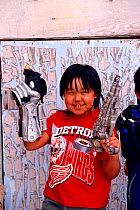 Inuit boy in American t-shirt playing with toy gun. Pond Inlet, Nunavut, Canada, 1999.