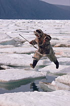 Inuit hunter jumping from one ice floe to another. Ellesmere Island, Nunavut, Canada, 1994.