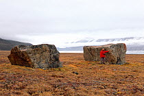 Tourist next to glacial erratics dropped by receding glacier. Alexandra Fiord, Ellesmere Island, Nunavut, Canada.