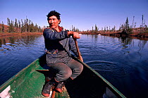 Cree Trapper paddling canoe while out hunting in autumn. Quebec, Canada, 1988.