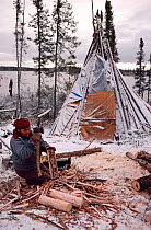 Cree woman chopping firewood at winter camp. Lake Bourinot, Canada, 1988.