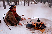 Lake Sami man cooking meat and coffee on fire. Inari, Finland, 1996.