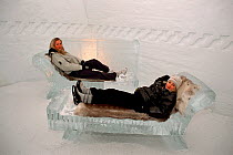 Girls resting on ice seats in the Ice Hotel., Jukkasjarvi, Sweden, 2003.