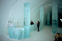 Reception area in Ice Hotel with ice desk and warmly dressed receptionist. Jukkasjarvi, Sweden, 2003.