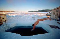 Tourist diving into the River Torne after sauna at the Ice Hotel. Jukkasjarvi. Sweden, 2003.