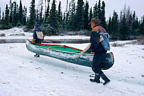 Two Innu men carrying canoe during Autumn hunting trip. Labrador, Canada, 1997.