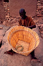 Dogon basket maker trimming basket. Mali, West Africa, 1981.