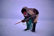 Inuit hunter waiting by seals breathing hole, with harpoon ready. Northwest Greenland, 1980.