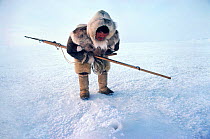 Fur clad Inuk waiting to harpoon seal at breathing hole. Northwest Greenland, 1980.