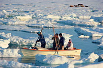 Inuit family manoeuvring open boat through melting summer sea ice in Inglefield Bay. Thule, Northwest Greenland, 1980.