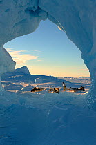 Inuit hunter with dog sled viewed through hole in iceberg near Savissivik. Northwest Greenland, 1996.