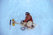 Inuit hunter lighting stove inside igloo. Northwest Greenland, 1986.