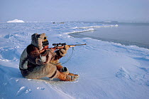 Inuit hunter shooting at seal from floe edge near Cape York, Northwest Greenland.