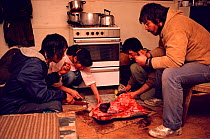 Inuit people sharing meal of muktuk (whale skin) and raw meat. Moriussaq, Northwest Greenland, 1987.