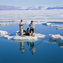 Inuit family using ice floe as raft to cross wide lead in early summer. Qaanaaq, Northwest Greenland, 1971.