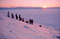 Inuit from Qaanaaq climbing hill behind their village to welcome the return of the sun on February 17th. Thule, Northwest Greenland, 1977.