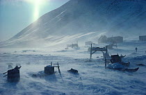 Storm blowing snow around sleds and houses in Inuit village of Siorapaluk. Thule, Northwest Greenland, 1977.