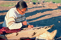 Inuit woman sewing wet seal skins onto wooden kayak frame. Qeqertat, Thule, Northwest Greenland, 1977.