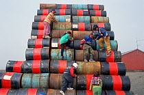 Inuit children playing on pile of empty oil drums. Moriussaq, Northwest Greenland, 1997.