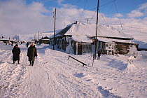 Villagers walking along Uelen's only street after winter storm. Chukotka, Siberia, Russia.