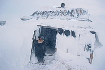 Chukchi hunter in doorway of hut during winter storm at Dezhnovka. Chukotskij Peninsula, Chukotka, Siberia, Russia.
