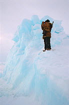 Chukchi hunter scanning sea ice for Polar bears from his vantage point on top of pressure ice. Chukotka, Siberia, Russia.