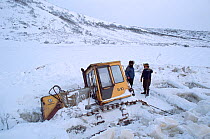 Workers trying to free bulldozer that has fallen through lake ice on winter road near Evensk. Magadan Region, Eastern Siberia, Russia, 2006.