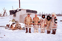 Nganasan men and women in traditional dress outside hut at a camp on the Kheta River. Taymyr, Northern Siberia, Russia, 2004.