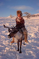 Yakut herder riding Reindeer / Caribou (Rangifer tarandus) at winter pastures near Verkhoyansk. Yakutia, Siberia, Russia, 1999.