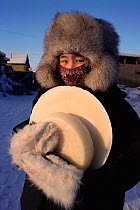 Girl carrying frozen milk back to her home in Verkhoyansk. Yakutia, Siberia, Russia, 1999.