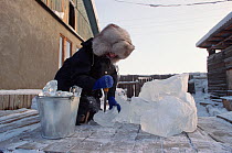 Girl breaking up pieces of river ice for drinking water. Verkhoyansk, Yakutia, Siberia, Russia, 1999.