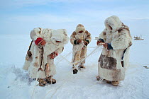 Nenets men checking fishing net set under ice on a lake in the Gydan Peninsula. Western Siberia, Russia, 2000.