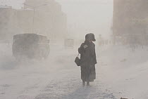 Woman struggling against the wind during winter storm in Norilsk. Western Siberia, Russia, 2000.