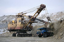 Giant digger loading ore into back of truck at an open mine near Norilsk. Western Siberia, Russia, 2000.