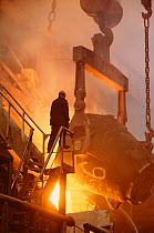 Worker silhouetted by red hot metal at the copper foundry in Norilsk. Western Siberia, Russia, 2000.