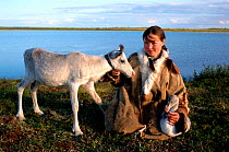 Nenets girl with pet Reindeer / Caribou calf (Rangifer tarandus) and Swan cygnet, probably Whistling swan (Cynus columbianus). Nadym Tundra, Yamal, Western Siberia, Russia, 2000.