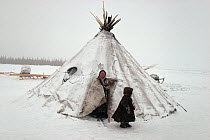 Nenets woman and boy at entrance to snow covered tent. Yamal, Siberia, Russia, 1993