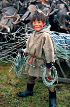 Nenets boy coiling his lasso as he stands by a Reindeer / Caribou (Rangifer tarandus) corral. Yamal, Siberia, Russia, 1993