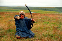 Nenets boy with bow and arrow hunting Ptarmigan. Yamal, Siberia, Russia, 1993.