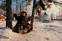 Nenets boy playing on a swing at Reindeer / Caribou herders' winter camp. Yamal, Siberia, Russia, 1996.
