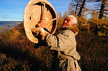 Elderly Nenets man holding sacred drum, which he made in 1946. Yamal, Western Siberia, Russia, 2001.